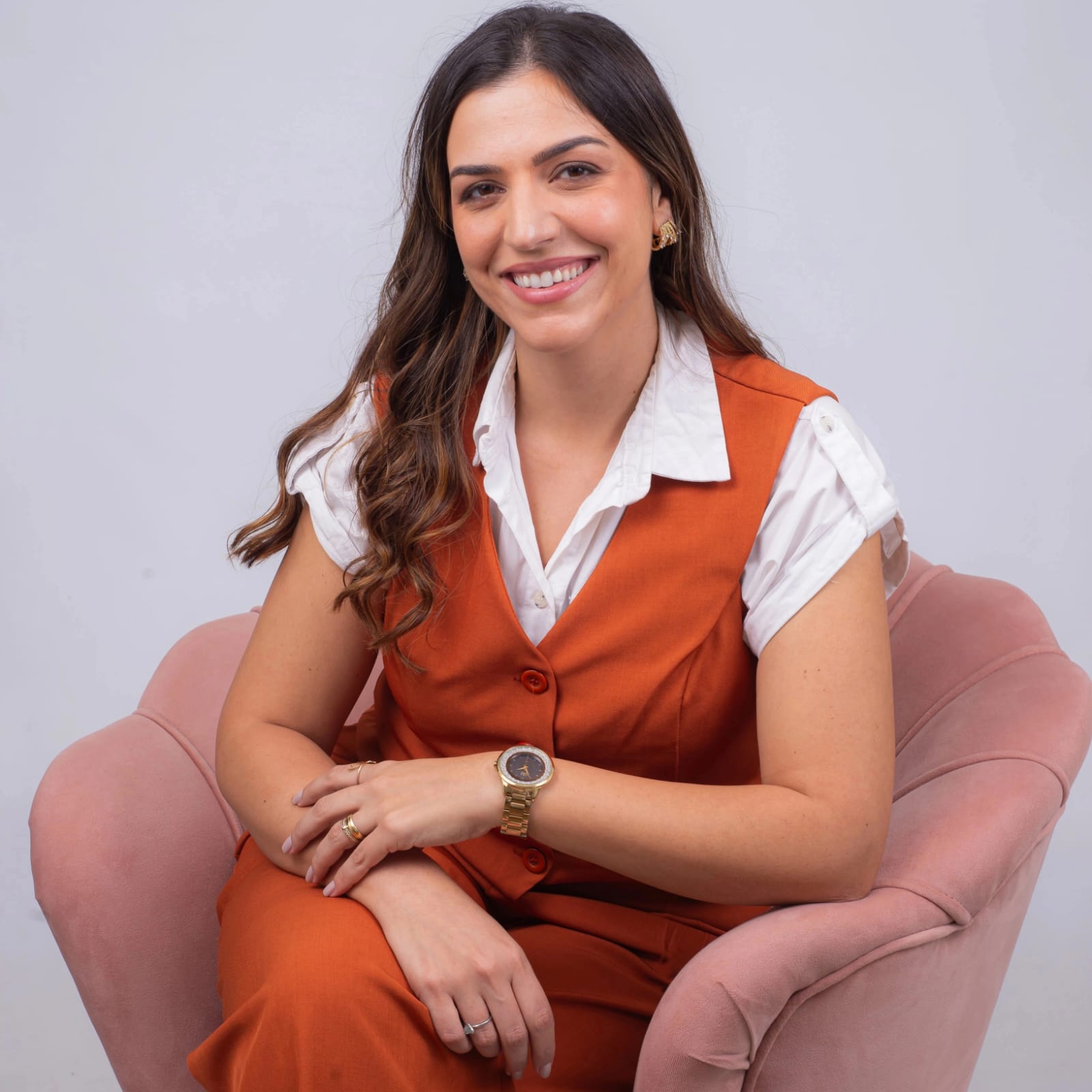 Priscila sentada em poltrona terracota